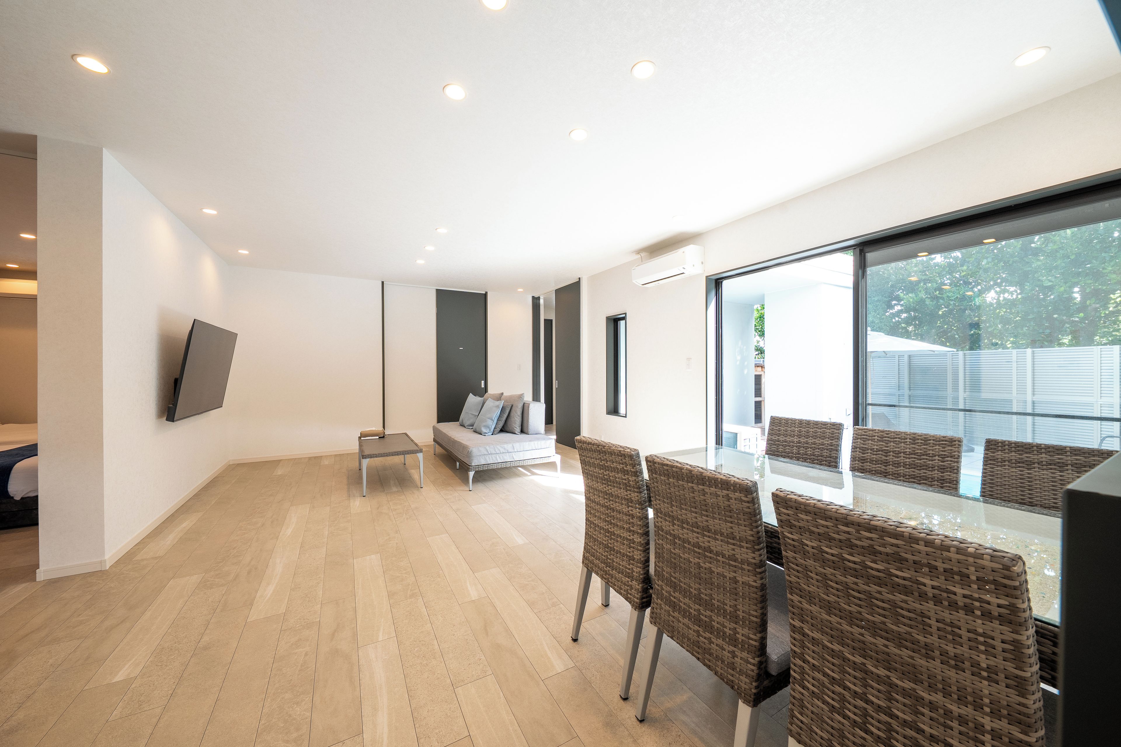A modern interior with a dining area, a sofa, and a TV mounted on the wall.
