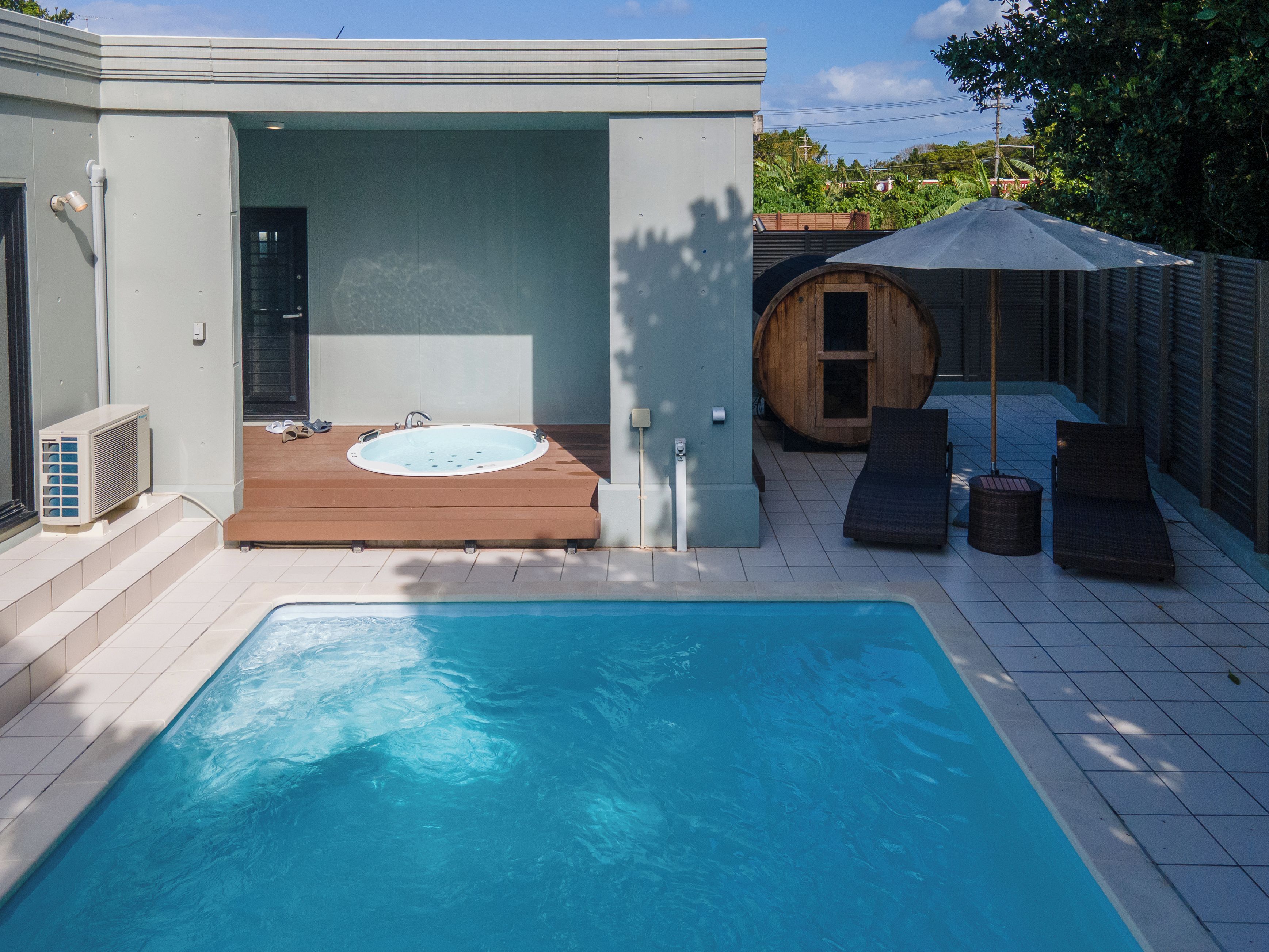 Een zwembad met een jacuzzi en ligbedden.