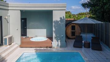 Een zwembad met een jacuzzi en ligbedden.
