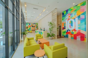 A hotel lobby with a reception desk, seating area, and colorful geometric wall design. - Hotel101 - Davao (Davao)