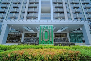 A modern hotel entrance with a prominent sign, a glass facade, and a landscaped area with shrubs. - Hotel101 - Davao (Davao)