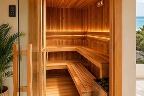 A wooden sauna with benches and a glass door, overlooking a tropical landscape. - Penthouse in Cabarete. Pool, Gym & Beach (Cabarete)