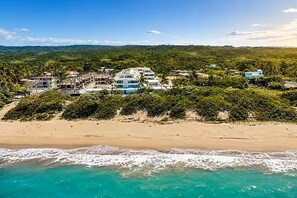 Eine Küstenimmobilie mit mehreren Gebäuden, einem Sandstrand und Blick auf den Ozean.
