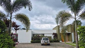Una casa moderna con camino de grava y un coche estacionado.