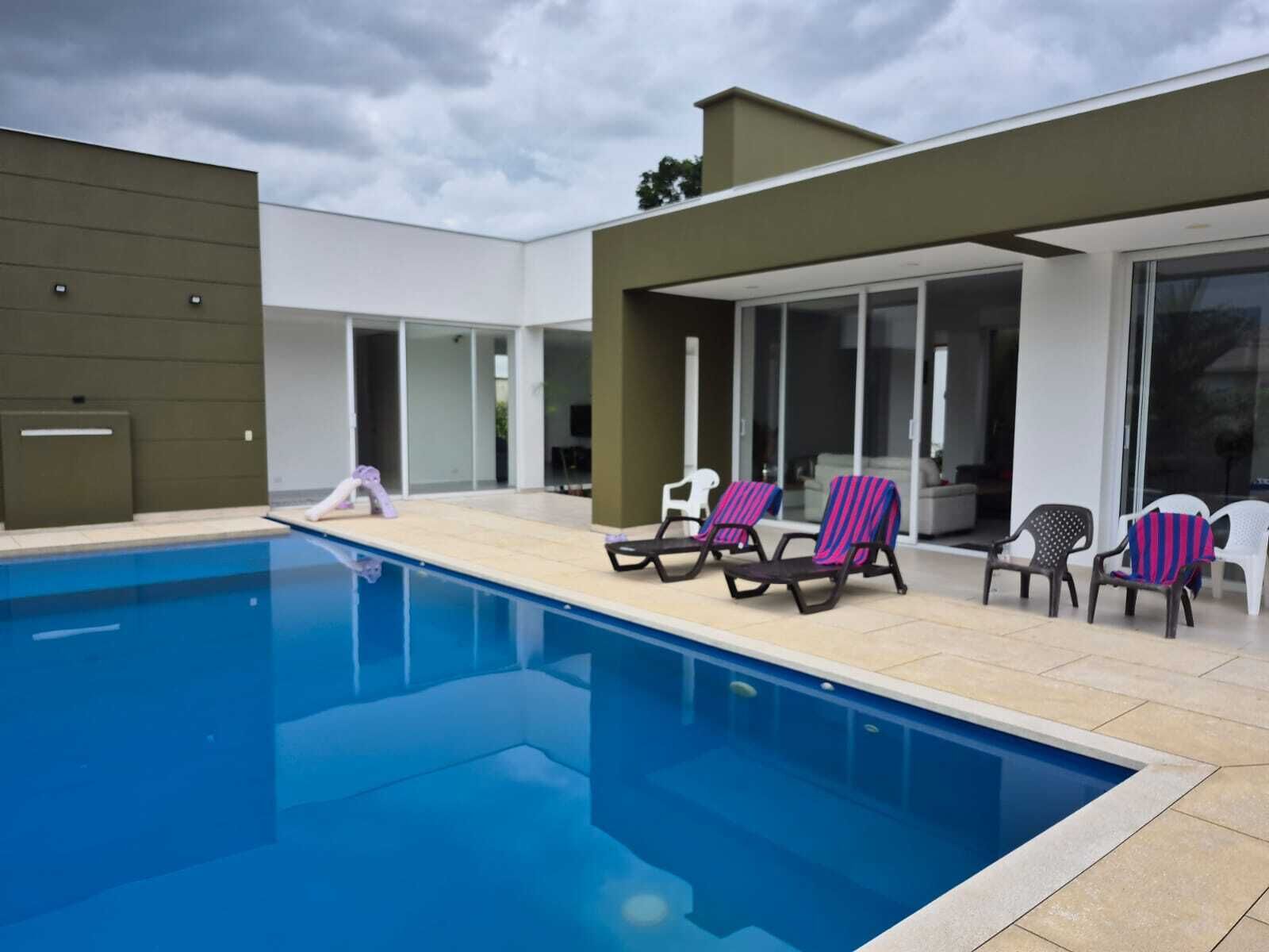 A modern outdoor pool area with lounge chairs and a covered patio.