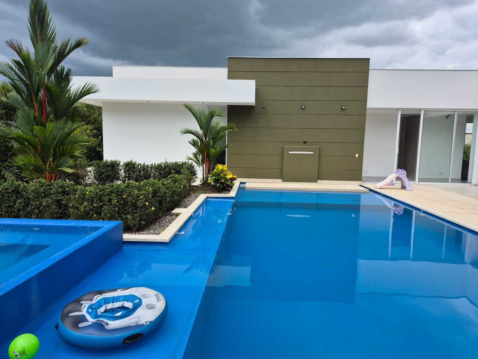 A swimming pool with a modern design, surrounded by greenery and a building with a flat facade.