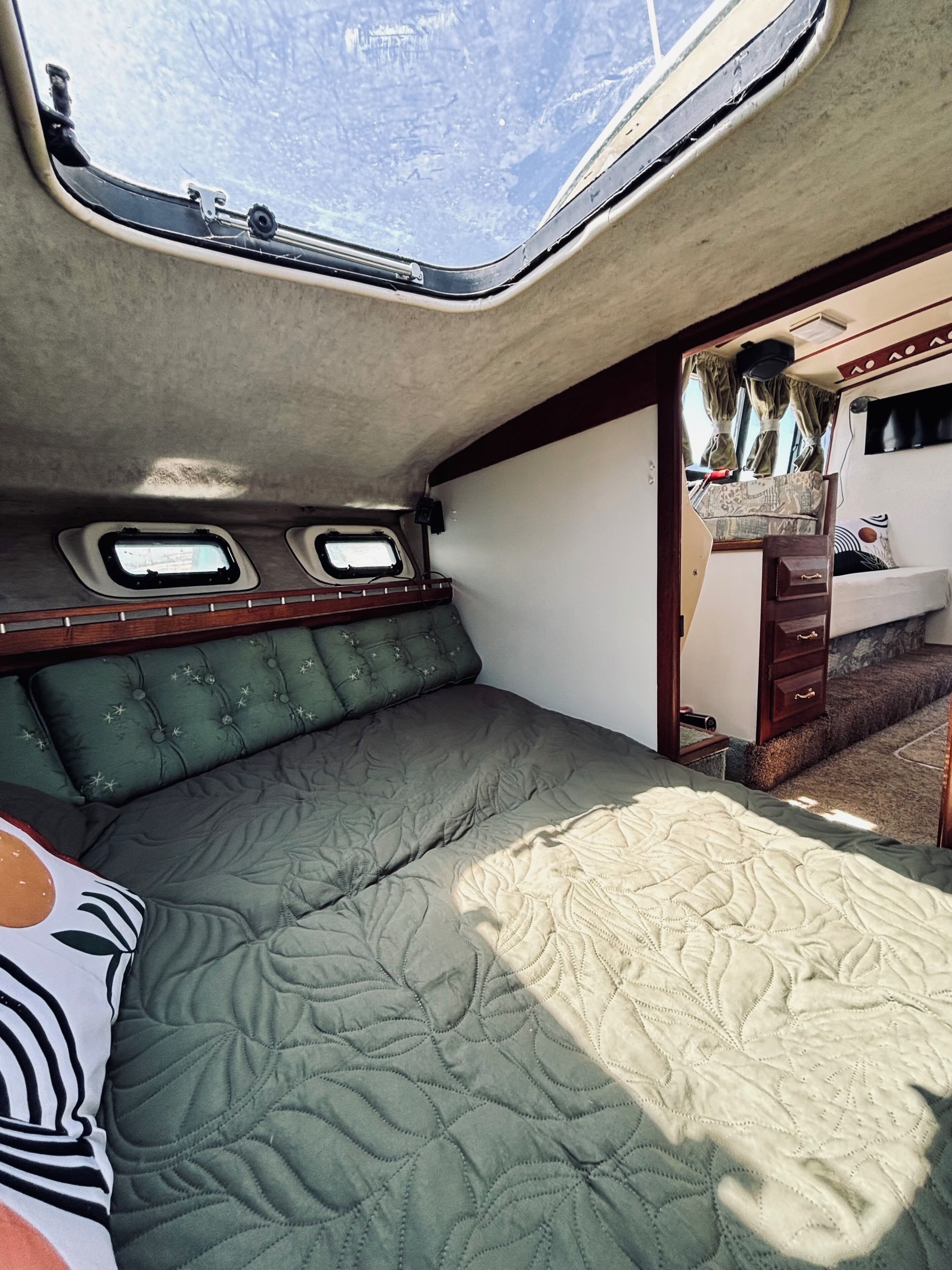 A compact interior with a bed, a small window, and a vanity area.