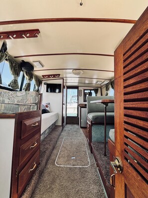 A compact RV interior with a kitchenette, a bed, and a seating area.