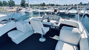 Interior de barco com assentos, um volante e painel de controle.