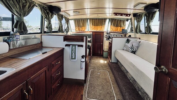 Interior compacto de uma motorhome, com cozinha compacta, área de refeições e espaço para dormir.