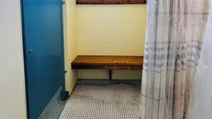 Um espaço pequeno e fechado, com um banco, uma janela e uma porta.