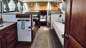 Interior compacto de uma motorhome com cozinha compacta, área de refeições e beliche.