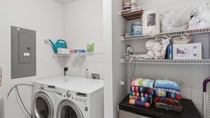 A laundry area with a washing machine, shelves with cleaning supplies, and a water heater. - Main Channel Views, 3 Heated Pools & Gated Resort (Lake Ozark)