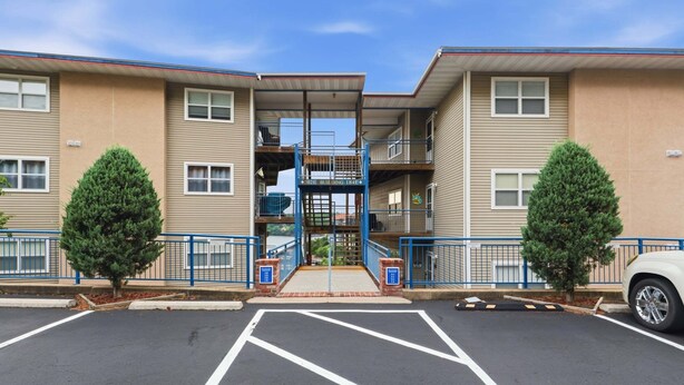 A multi-story residential building with a central staircase, parking lot, and two trees. - Main Channel Views, 3 Heated Pools & Gated Resort (Lake Ozark)