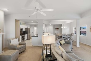 A spacious living area with a ceiling fan, a sofa, a coffee table, and a dining area with chairs. - Main Channel Views, 3 Heated Pools & Gated Resort (Lake Ozark)