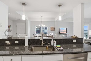 A modern kitchen with a granite countertop, stainless steel sink, and pendant lighting. - Main Channel Views, 3 Heated Pools & Gated Resort (Lake Ozark)