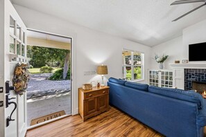 Ein Wohnzimmer mit blauem Sofa, Holzschrank und Kamin.