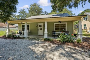A covered porch with a gravel driveway, a front door, and a small seating area with chairs. - Stella Marina - Hosted by Moore AI Rentals (Fernandina Beach)