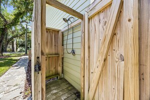 A wooden outdoor shower structure with a metal showerhead and a hose. - Stella Marina - Hosted by Moore AI Rentals (Fernandina Beach)