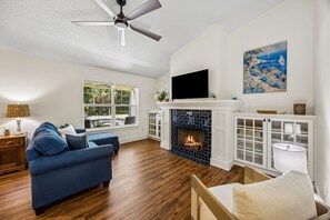 Ein Wohnzimmer mit Kamin, Fernseher und Deckenventilator.