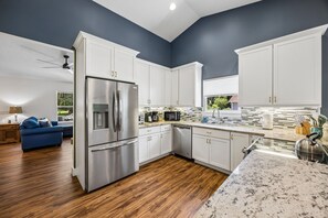 A modern kitchen with white cabinets, a stainless steel refrigerator, and a granite countertop.