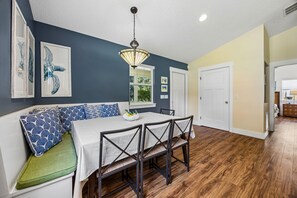 A dining area with a table and chairs, a ceiling light, and artwork on the walls. - Stella Marina - Hosted by Moore AI Rentals (Fernandina Beach)