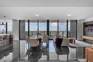 A modern living room with a large panoramic window, a dining area, and a seating arrangement. - E11EVEN 61st Floor Penthouse | 2BR + Balcony (Miami)