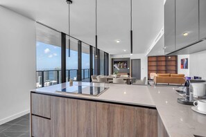 A modern interior with a large kitchen island, dining area, and seating space with a city view. - E11EVEN 61st Floor Penthouse | 2BR + Balcony (Miami)
