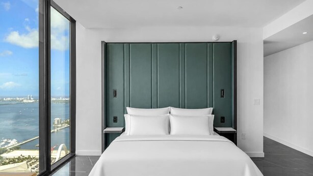 Et moderne hotelværelse med en stor seng, havudsigt og bypanorama.
