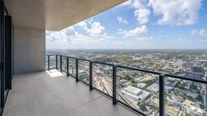 En balkon med udsigt over byen, gelænder af metal og betonloft.
