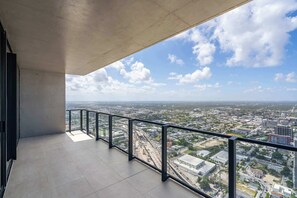 Ein Balkon mit Blick auf die Stadt, einem Metallgeländer und einer Betonbrüstung.