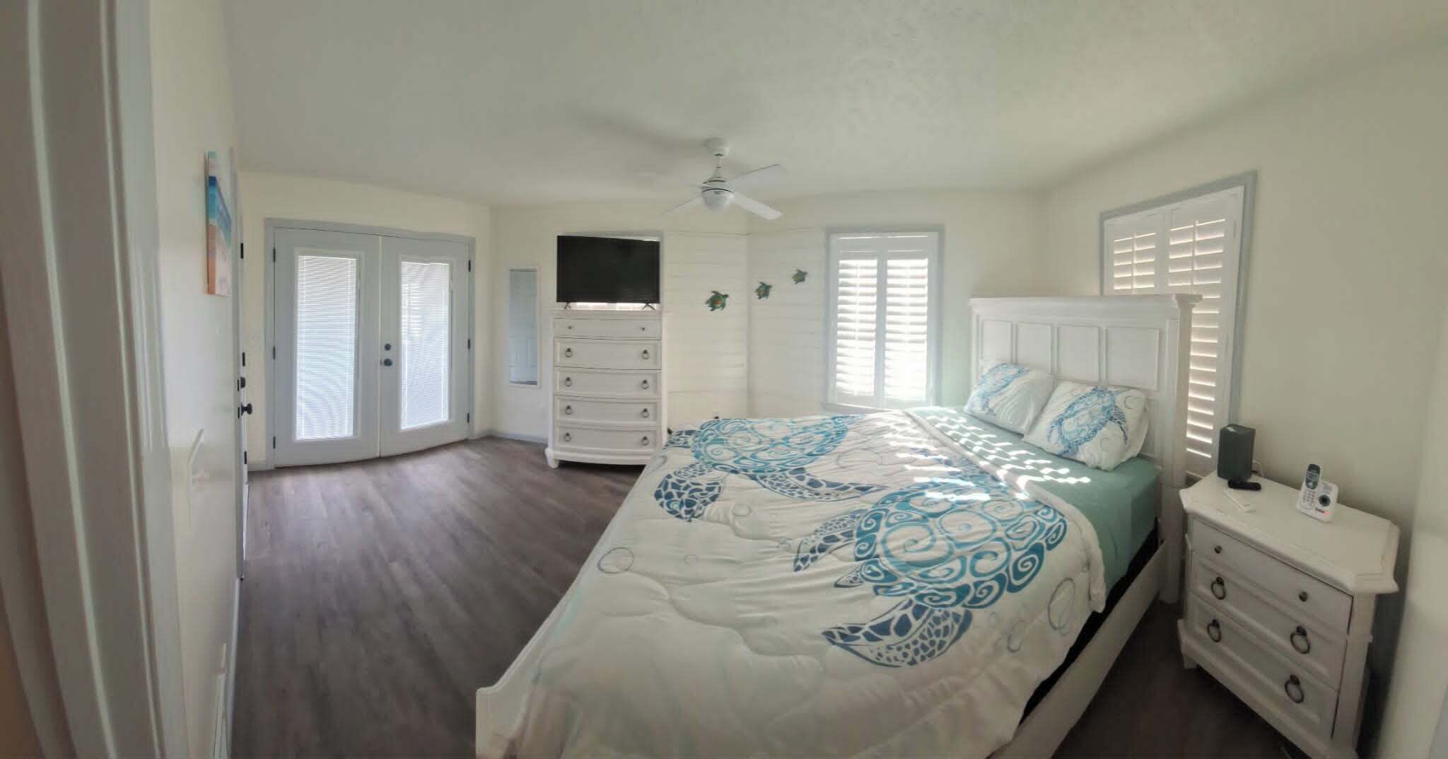 Une chambre à coucher avec un lit, une commode et un ventilateur de plafond.