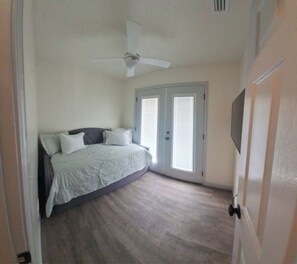 A bedroom with a bed, a ceiling fan, and a door with a window. - The Pelican Roost - Steinhatchee, FL (Steinhatchee)
