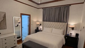 A bedroom with a large bed, bedside tables, a dresser, a mirror, and a ceiling fan. - The Knickerbocker by Delphius (Tampa)