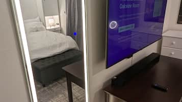 Une chambre d’hôtel avec un grand miroir, un lit, une télévision et un bureau.