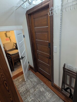 A hallway with a wooden door, a chair, and a small table.