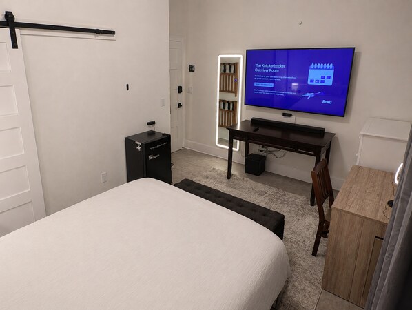 A hotel room with a bed, a desk, a television displaying a menu, a wardrobe, and a door.