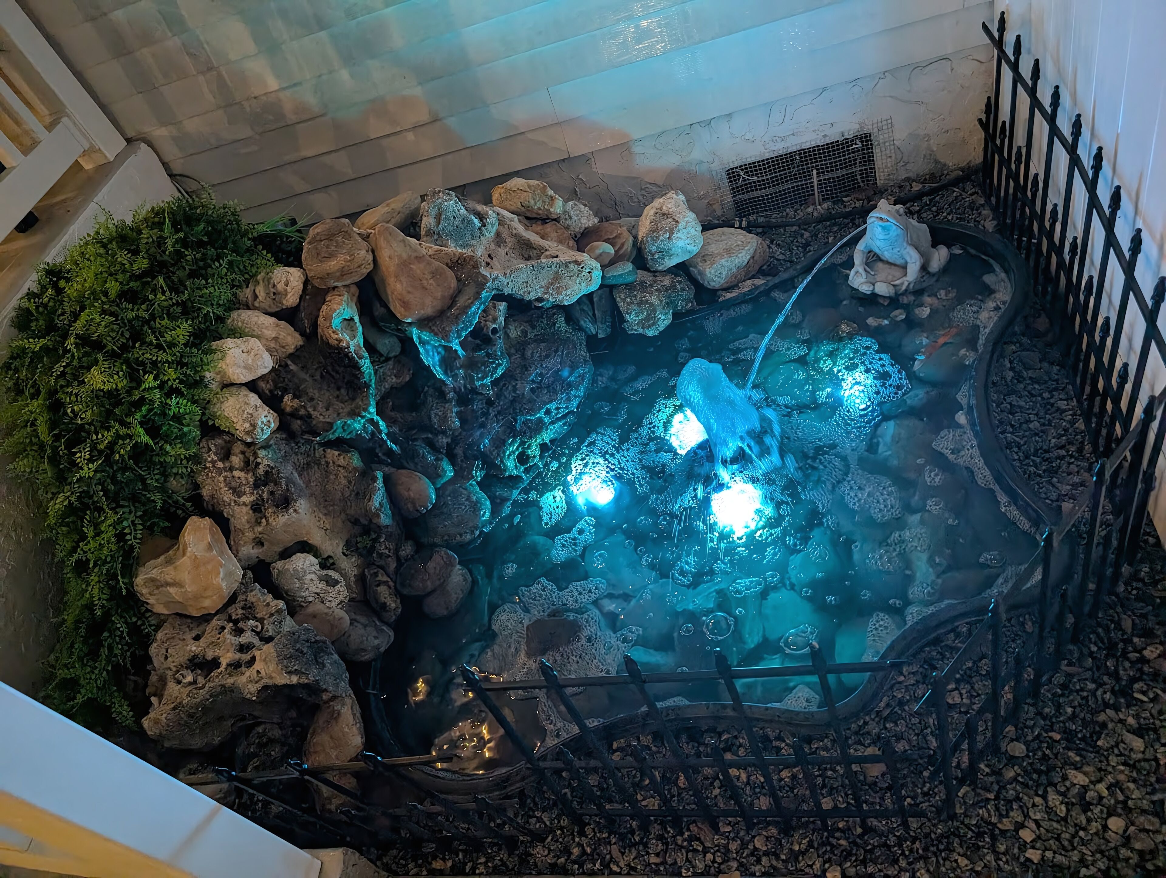 Un petit bassin intérieur agrémenté de rochers, d’un pont et d’une clôture.