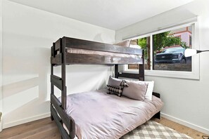 A bunk bed with a headboard, a window with a view of a car and building, and a small rug on the floor. - Four Seasons Retreat | Minutes to Skiing and Downtown (Ketchum)