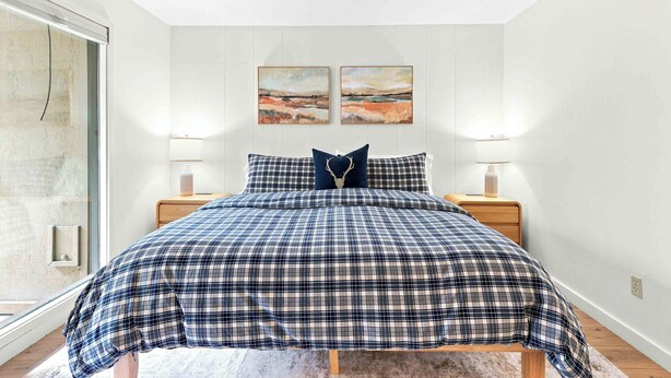 A bedroom with a bed, two nightstands, a window, and two wall-mounted paintings. - Four Seasons Retreat | Minutes to Skiing and Downtown (Ketchum)