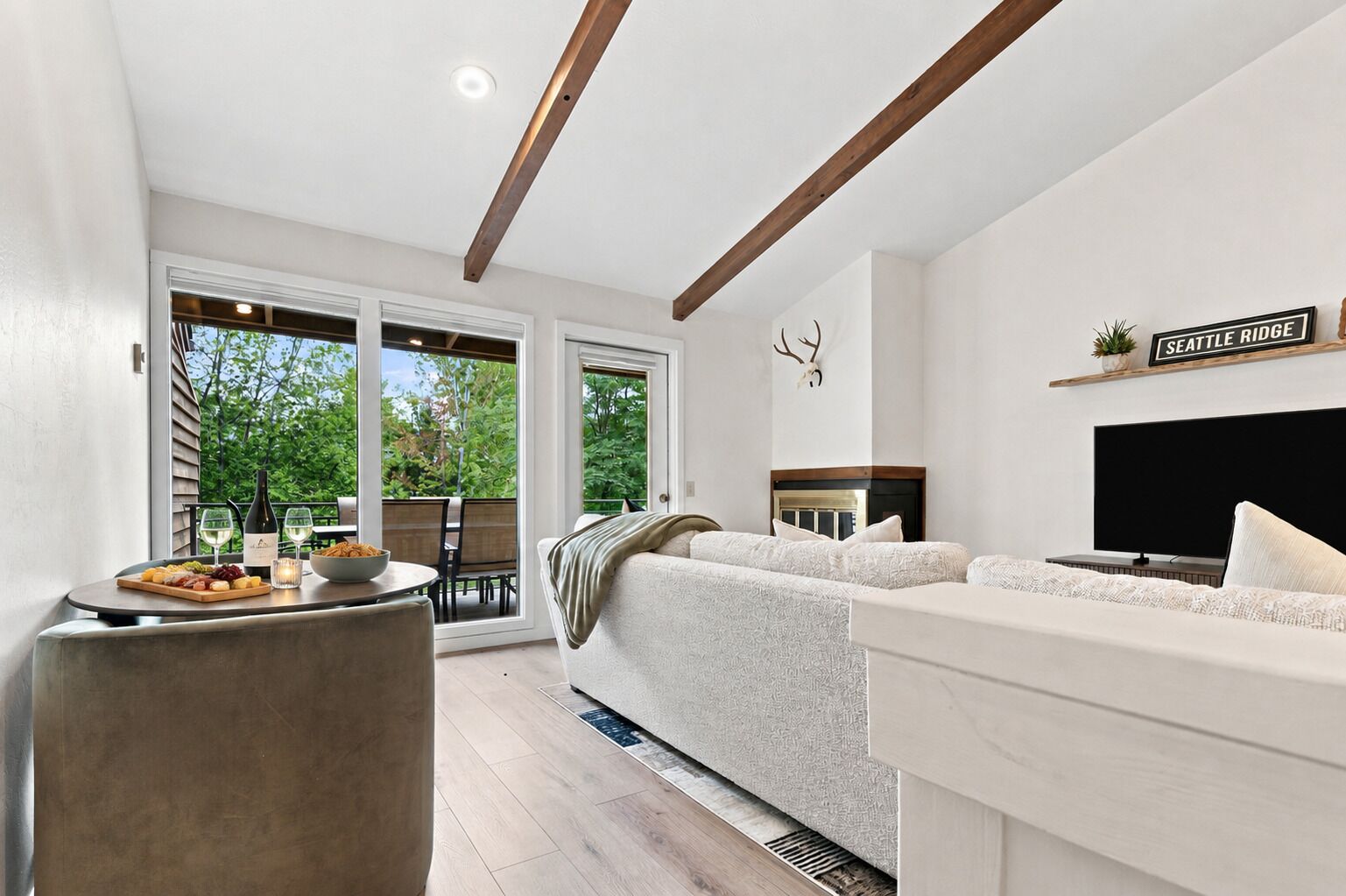 A modern living room with a sofa, a television, and a dining area with a table set for two.