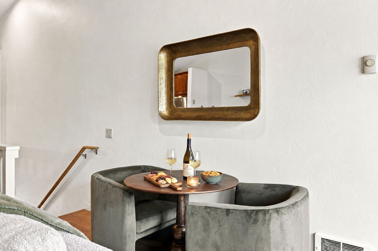 Un intérieur moderne avec une table ronde, un miroir et une bouteille de vin.
