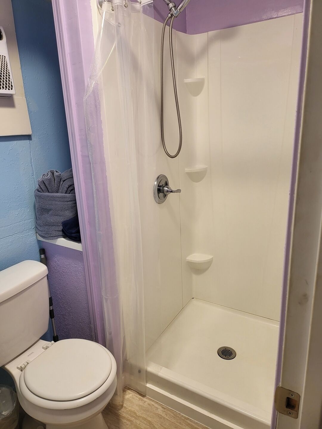 A bathroom with a white toilet, a shower enclosure, and a towel rack.