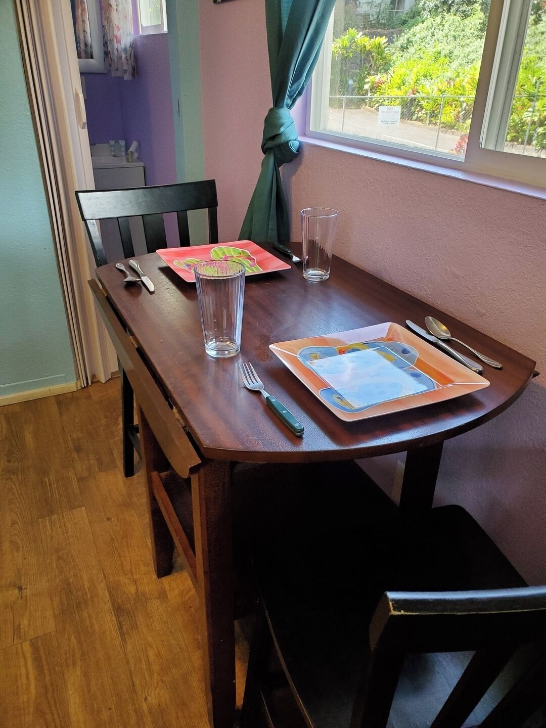 Ein Esstisch mit Platzsetzer, Besteck und zwei Gläsern.