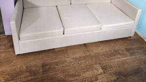 Ein beiges Sofa in einem Raum mit Holzboden und einer blauen Wand.