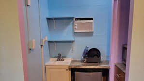 Una cucina compatta con lavandino, un piccolo frigorifero e un forno a microonde.