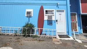 Un edificio con facciata blu, due finestre, una porta e una tavola da surf rossa montata al muro.