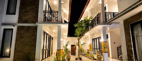 A modern hotel with a swimming pool, multiple balconies, and a well-lit outdoor area.