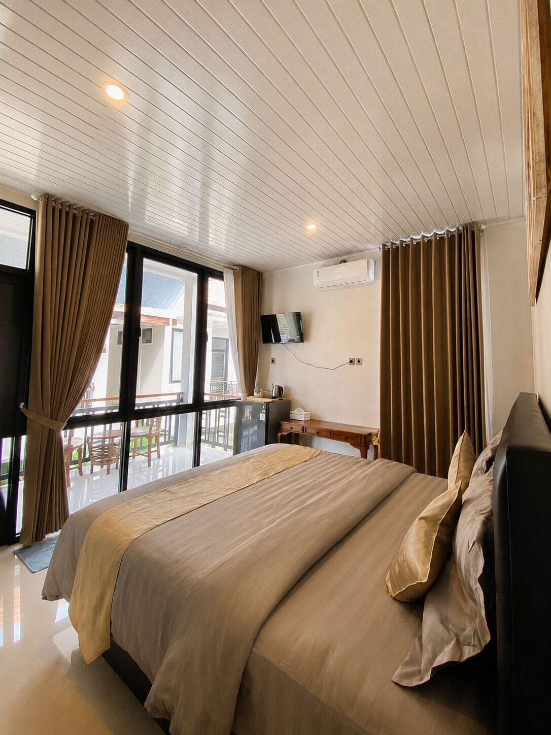 Et hotelværelse med en stor seng, et fjernsyn, en aircondition og en balkon med udsigt.