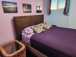 A bed with a purple quilt, two patterned pillows, and a wooden headboard. - Heart of Wailuku • Queen Bed + Kitchenette (Wailuku)